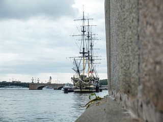 old ship with sails and granite embankment. Saint-Petersburg, Russia