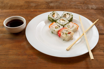 Assorted different fish rolls on a white plate.