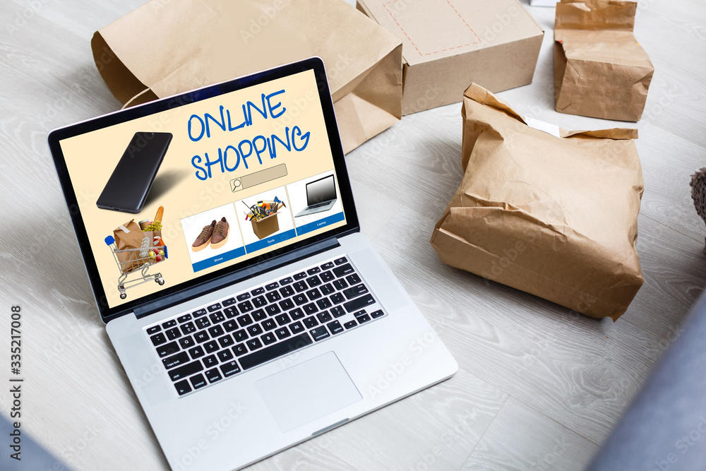 Poster laptop with onlain shopping site on the screen stands on the table in the office with phone and watc