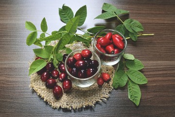Owoce dzikiej róży i żurawina na stole z zielonymi liśćmi    © Aneta