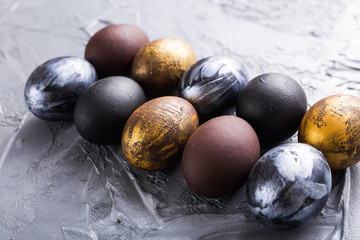 Holidays, traditions and Easter concept - Dark stylish easter eggs on grey background.