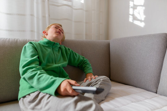 Tired Young Boy Watching Tv And Falling Asleep On The Couch At Home