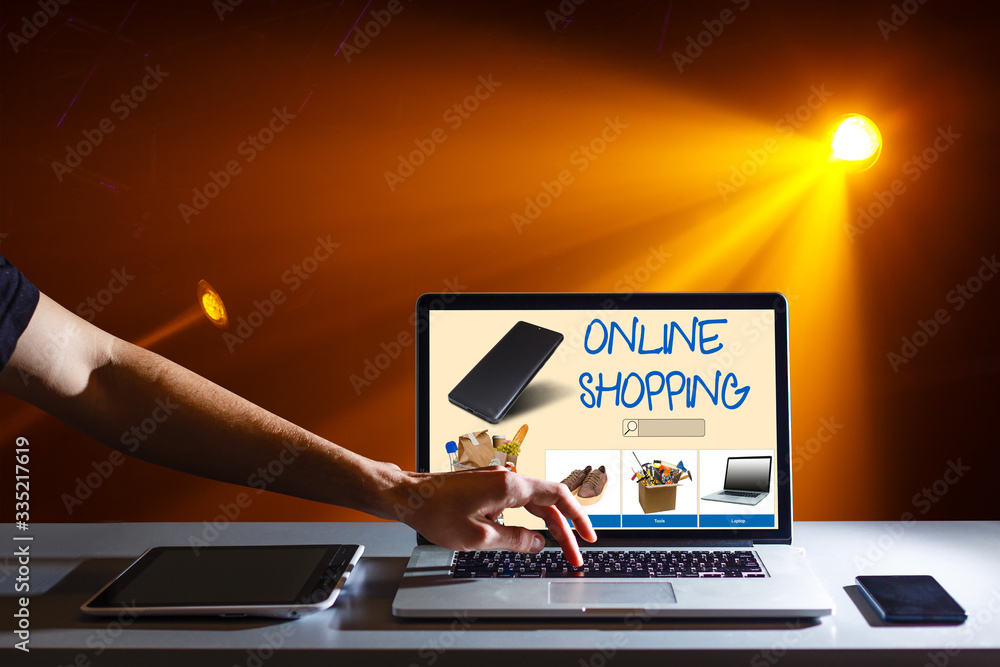 Poster laptop with onlain shopping site on the screen stands on the table in the office with phone and watc