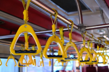 Yellow plastic handles on a metal handrail on the bus.