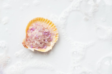 Sea shell filled with pink sea salt, on a white background.
