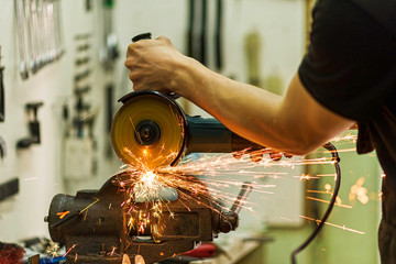 Close-up of a mechanic working as a grinder, sparks fly.