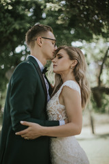 Portrait of a lovely bride and groom embrace, kiss and hug each other. Couple in love in the bosom...