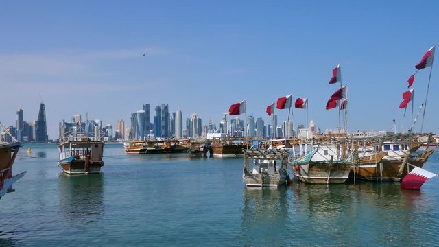 Traditional Dhow, Arab sailing vessels with Qatar flags in the harbour with the Doha skyline in the background
