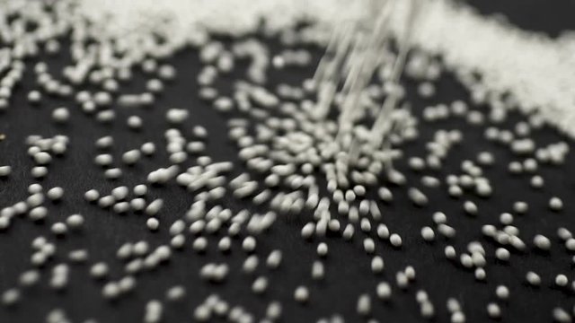 White granules of medicine crumble on a black background close-up slow motion