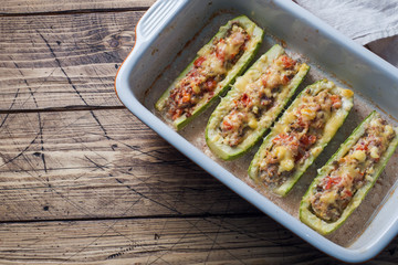 Baked stuffed zucchini boats with minced chicken mushrooms and vegetables with cheese on a baking sheet. Top view Copy space