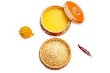Homemade ghee, rice in a ceramic pot, red peppers and turmeric spices. Isolated white background.