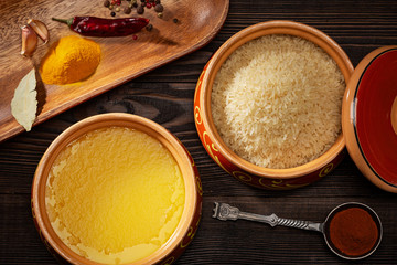 Homemade ghee, rice in a ceramic pot, red peppers and turmeric spices.