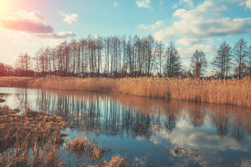 Fototapeta premium View of the river on the meadow in evening at sunset light. Beautiful nature landscape with the bright evening sky