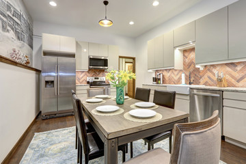 Dining room with rustic mural of old village and modern kitchen shiny beige cabinets, rustic brick backsplash.