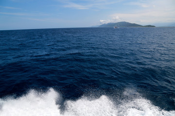 The ship sailed on the azure Pacific Ocean, with a beautiful green island in the distance