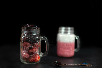 Summer berry cocktail with chia seeds in vegetable milk in glass glasses on a dark background.
