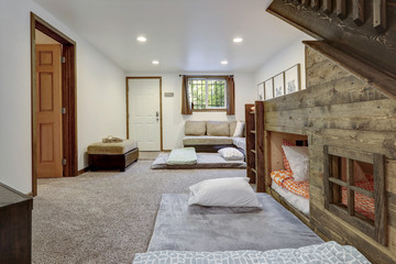Living room interior with beige sofa, natural touches, custom build wooden bunk bed, tall ceiling with loft.