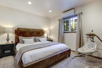 Elegant cozy bedroom with brown suede king size bed, white linen and baby swing all in natural calm tones.