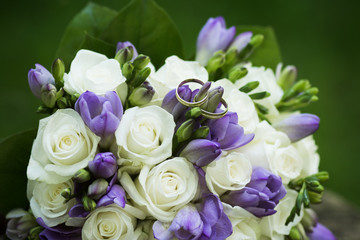 wedding bouquet of white and lila flowers with rings, close up view of white roses