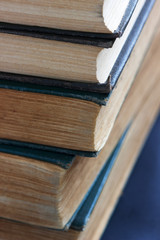 Old books with frayed covers on a dark table.