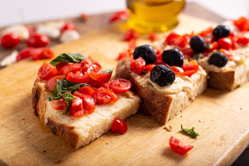 Mix of bruschette with cherry tomatoes and cream cheese, hummus and black olives. Italian food, healthy appetizer