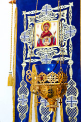 Church lamp in front of the icon. A burning lamp, a candle in a blue flask sways in front of the iconostasis, in a beautiful candlestick in the Orthodox Church. Macro, macro. The concept of Orthodoxy.