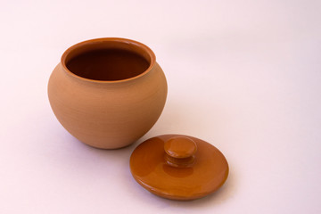 Clay brown pot with a lid close-up close-up on a white background. Clay jug for the kitchen. The concept of food ecology.