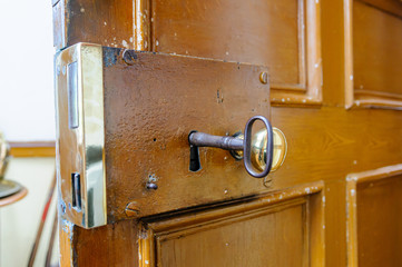 Heavy brass lock on the inside of a door, with a large old-fashioned key.