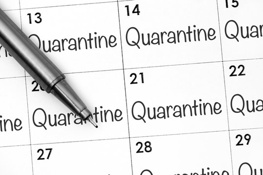 Calendar page with words Quarantine with pen.