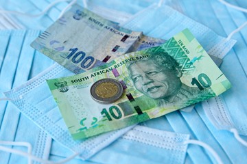 Obraz premium South African money on top of medical face masks. Cost of preventing infectious viruses such as the coronavirus (Covid-19) concept image.
