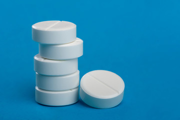 A few white pills with a column on a blue background. Macro photo. Close-up. Free space for text.