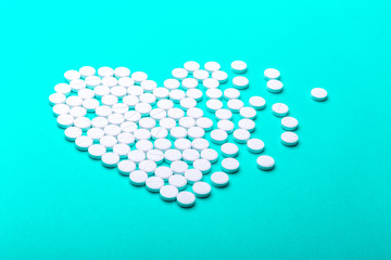 Heart of pills on a green background.