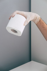 A medical worker in rubber latex glove on his hand holds toilet paper roll . Concept of coronavirus panic. Isometric and geometric style.