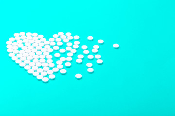 Heart of pills on a green background.