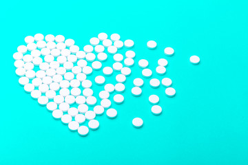 Heart of pills on a green background.