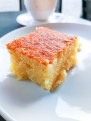 Delicious sweet orange cake, traditional greek pastry baked with orange pieces and honey, served in white plate.