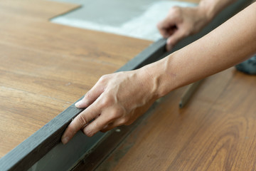 Fototapeta na wymiar close up of working hands matching floor nosing color for vinyl floor tile step 