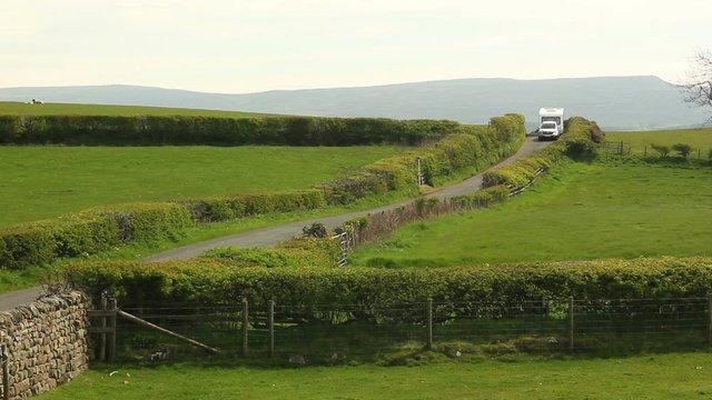 Car & Caravan (Trailer) driving down the road / country lane on a summer day - Staycation. Stock Video Clip Footage. Wide Shot