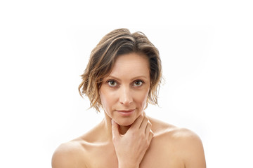 Beautiful young woman looking at the camera and touching her face. Clean skin. Naked to the shoulders posing. isolated white background.