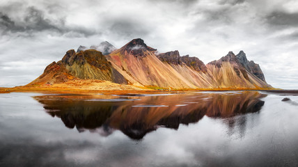 Gorgeous landscape of the famous Stokksnes mountains on Vestrahorn cape. Reflection in the clear water on the epic skies background, Iceland