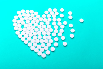 Heart of pills on a green background.