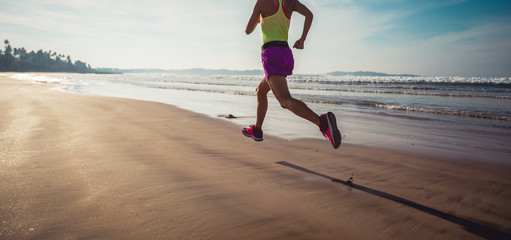 Fitness woman runner running on sunrise beach