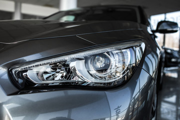 Fototapeta premium Modern luxury car close-up. Concept of expensive, sports auto. Headlight lamp of new cars,copy space. A modern and elegant car illuminated.