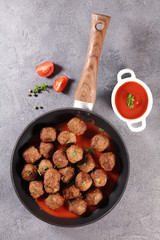 fried meatball in pan with tomato sauce