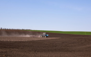 A tractor in the field cultivates the soil for sowing