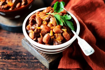 Beef stew with beans, tomatoes and vegetables on a dark wooden background