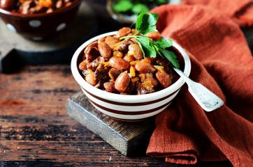 Beef stew with beans, tomatoes and vegetables on a dark wooden background