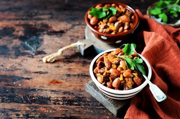Beef stew with beans, tomatoes and vegetables on a dark wooden background