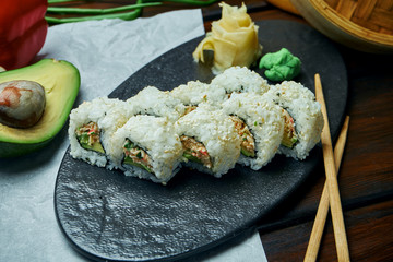 Classic japanese sushi rolls with soft crab avocado. California roll on a black plate with chopsticks. Japanese cuisine. Healthy seafood