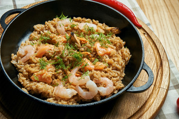 Pad thai or phad thai - a classic Thai dish wok fried rice noodles with shrimps and vegetables in a black plate on a wooden background. Close up